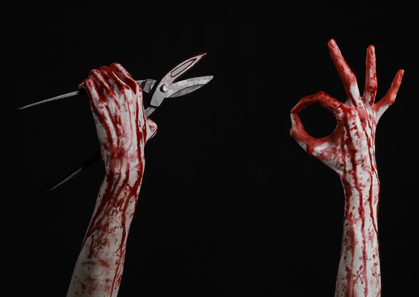 Halloween theme: bloody hand holding a big old bloody scissors on a black background - Fotoğraf, Görsel