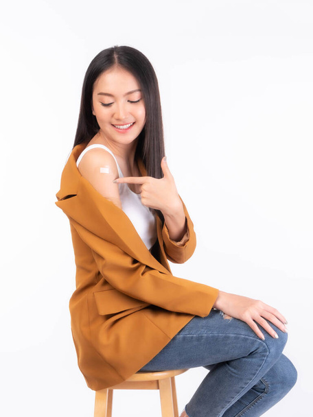 Güzel Asyalı genç kadın gülümseyip kollarını işaret ediyor. Kovid 19 aşısından sonra antivirüs aşısı yaptırıyor. Uzayın fotokopisini çekin. - Fotoğraf, Görsel