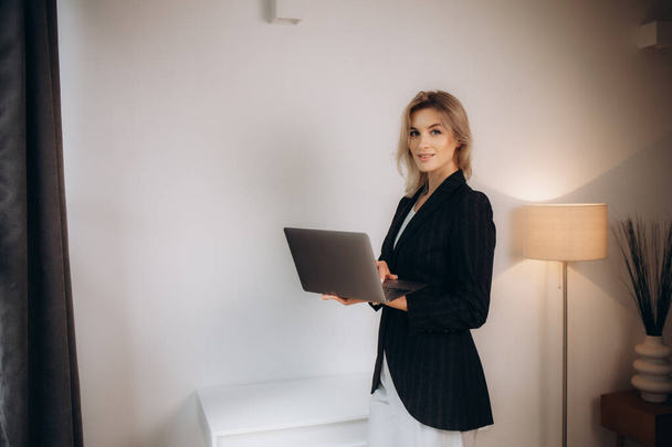 Femme assise sur le bord du bureau et utilise un ordinateur portable - Photo, image