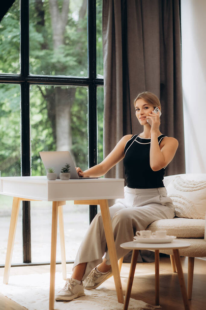 Happy woman using mobile phone and laptops for work. Confident business woman working from home. Home office. - Foto, Imagen