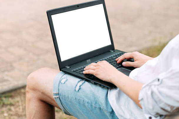 Portrait of a handsome man working with laptop sitting on a bench - Foto, Imagen