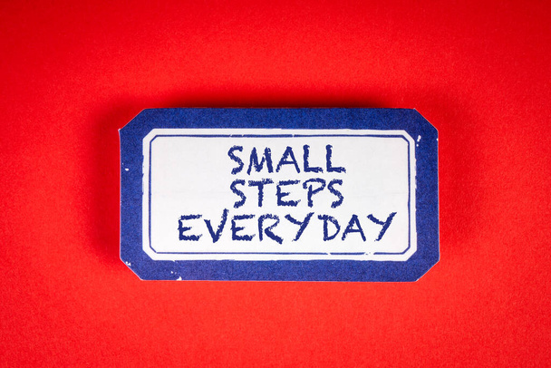 A kis lépések minden nap megtörténnek. Ragacsos megjegyzés szöveggel a piros háttér. - Fotó, kép