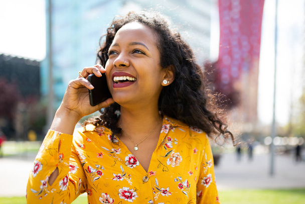 Közelkép portré mosolygós fiatal afrikai nő beszél a mobiltelefon áll odakint - Fotó, kép