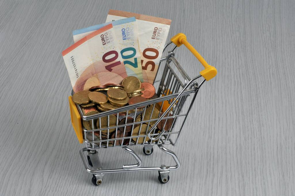 Koncepcja siły nabywczej z wózkiem supermarketowym pełnym euro z bliska na szarym tle  - Zdjęcie, obraz