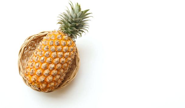 fresco una piña (ananas comosus (l.) merr) maduro amarillo orgánico en una cesta de bambú aislado sobre un fondo blanco. concepto de frutas de verano. - Foto, Imagen