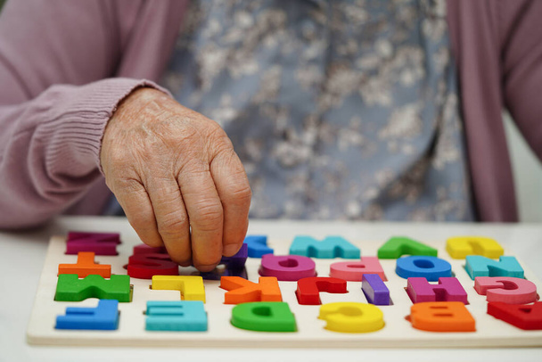 Ázsiai idős nő játszik kirakós játék gyakorolni agy képzés demencia megelőzésére, Alzheimer-kór. - Fotó, kép