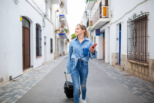 Retrato de una joven viajera caminando con teléfono móvil y bolso - Foto, imagen