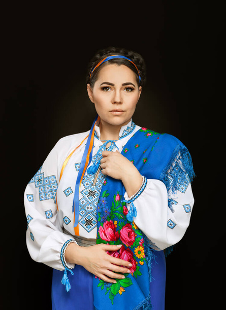 Beautiful Ukrainian woman in national costume. Attractive Ukrainian woman wearing in traditional Ukrainian embroidery vyshyvanka, at black background. - Photo, Image