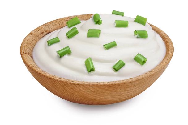 crème sure ou yaourt dans un bol en bois avec oignon vert isolé sur fond blanc avec pleine profondeur de champ. - Photo, image