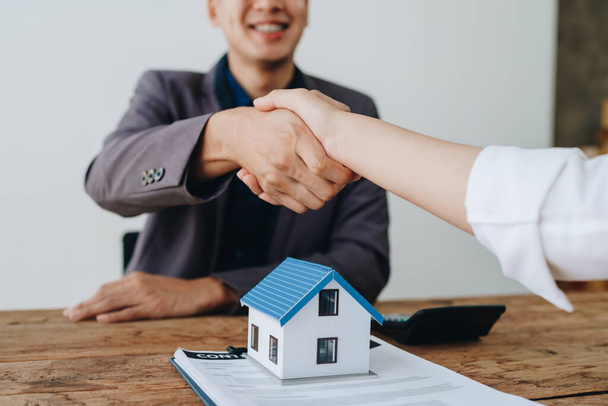 Die Hypothekenbeauftragten der Banken schütteln den Kunden die Hand, um ihnen zu gratulieren, nachdem sie einen Vertrag über einen Immobilienkredit unterzeichnet haben. - Foto, Bild
