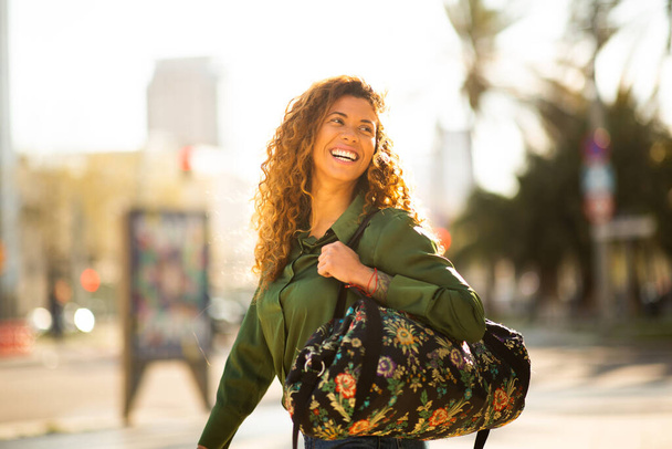 Portrait de belle jeune femme marchant dehors dans la ville portant un sac - Photo, image