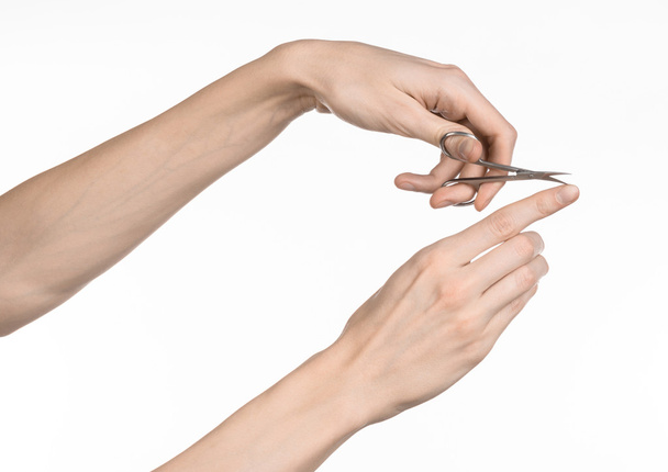 Zdrowie i higiena osobista: ręka trzyma nożyczki do manicure na białym tle - Zdjęcie, obraz