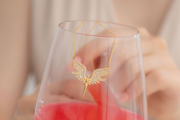 Vrouw vitrines sieraden met een glas roze drankjes. Deel afbeeldingen voor e-commerce, sociale media, product verkoop. - Foto, afbeelding