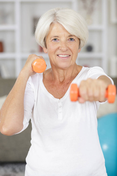 cheerful senior woman smiling at the camera with dumbbells - Fotografie, Obrázek