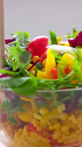 wooden spoons stir salad in glass plate corn tomatoes cucumbers bulgarian yellow peppers arugula leaves vegetarian food lunch slimming diet close-up female hands - Séquence, vidéo