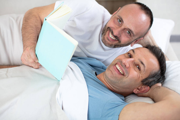 male couple in bed holding a book - Foto, immagini