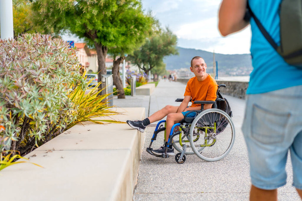 Een gehandicapte in een rolstoel naast het strand met vrienden - Foto, afbeelding