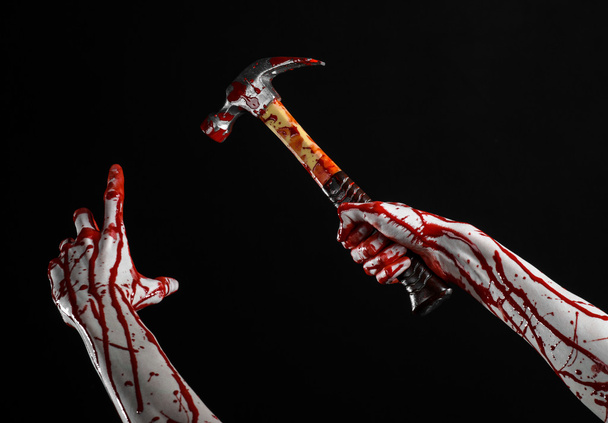 Bloody halloween theme: bloody hand holding a bloody hammer isolated on a black background - Fotografie, Obrázek