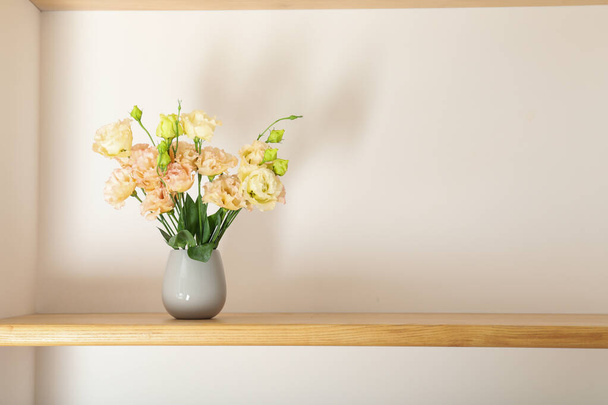 A beautiful vase with flowers on a shelf - Фото, зображення