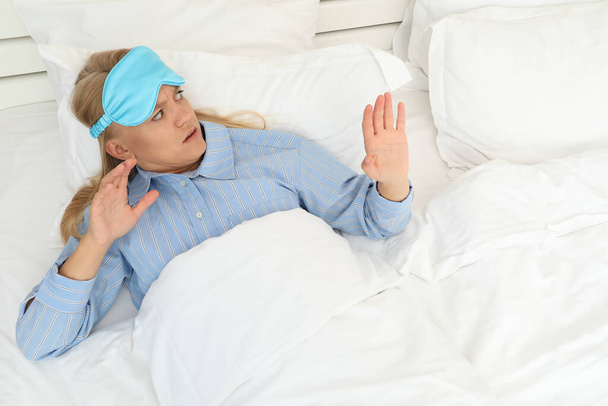 A frightened young woman in a sleeping mask has just woken up - Foto, Bild