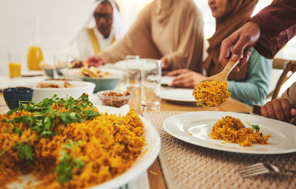 Jedzenie, zbliżenie i muzułmanin z dużą rodziną przy stole na eid mubarak, Islamskie święto i obiad. Ramadan festiwal, kultura i iftar z ludźmi jedzącymi w domu na post, islam lub religijne wakacje. - Zdjęcie, obraz