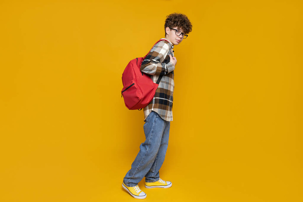 A teenager in glasses with a briefcase on a yellow background - Fotoğraf, Görsel