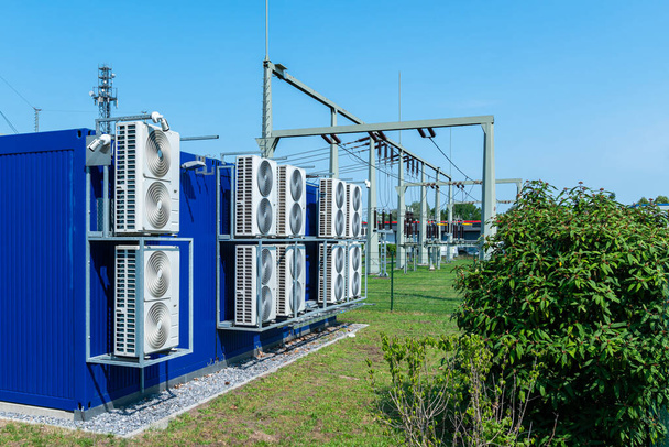 Transformatorkraftwerk mit großen Kühlventilatoren an der Rückwand. Blauer Himmel und grüne Büsche. - Foto, Bild