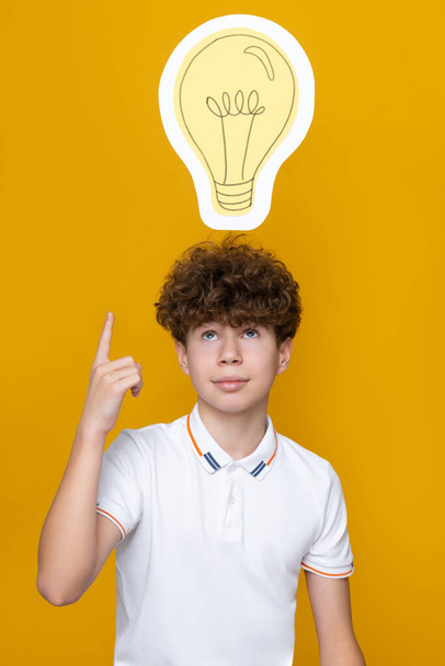Um adolescente de cabelos encaracolados teve uma ideia, uma lâmpada - Foto, Imagem
