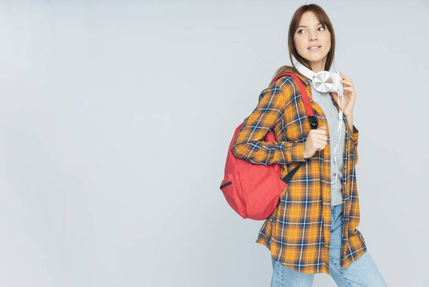 Attractive young woman with backpack on gray background, place for text - Photo, Image