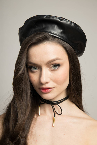 Attractive brunette in a black beret on a gray background - 写真・画像