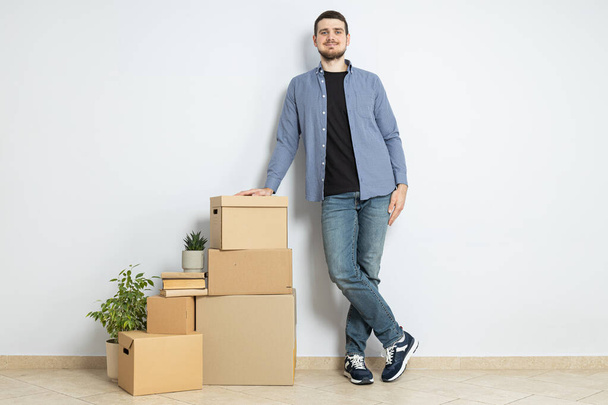 Moving concept, man with boxes leaning on boxes - Photo, Image