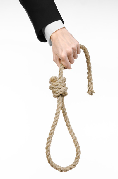 Suicide and business topic: Hand of a businessman in a black jacket holding a loop of rope for hanging on white isolated background - Fotó, kép