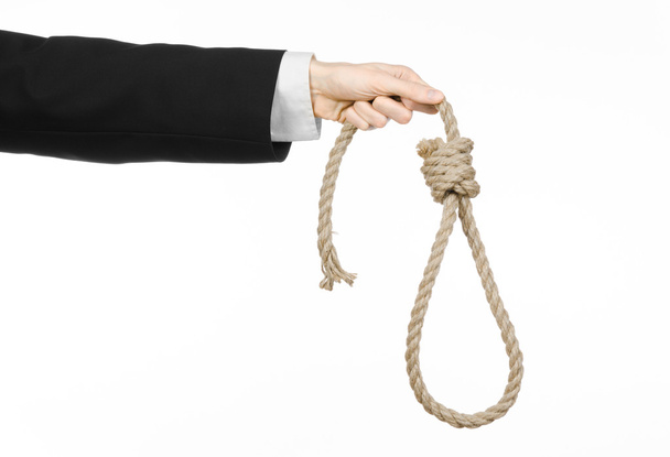 Suicide and business topic: Hand of a businessman in a black jacket holding a loop of rope for hanging on white isolated background - 写真・画像