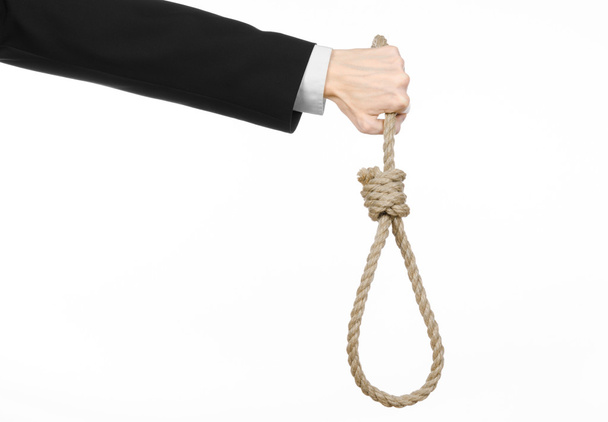 Suicide and business topic: Hand of a businessman in a black jacket holding a loop of rope for hanging on white isolated background - Фото, изображение