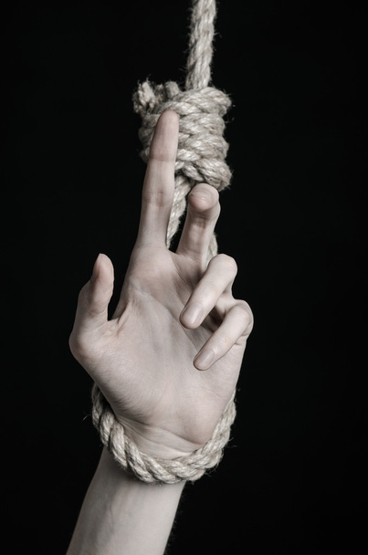 Suicide and depression topic: human hand hanging on rope loop on a black background - Photo, image