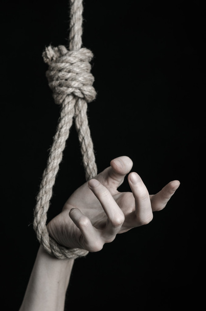 Suicide and depression topic: human hand hanging on rope loop on a black background - Fotografie, Obrázek
