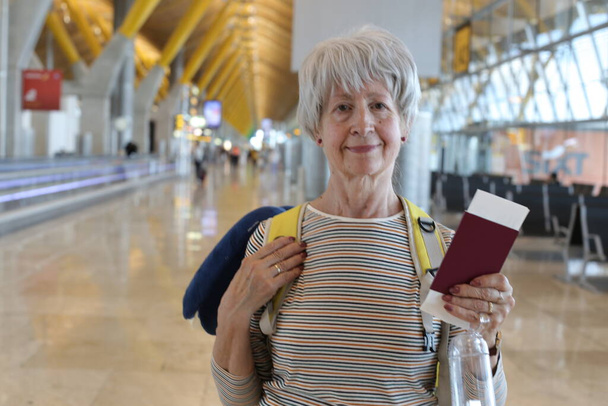 close-up portrait of mature woman with passport at airport - 写真・画像