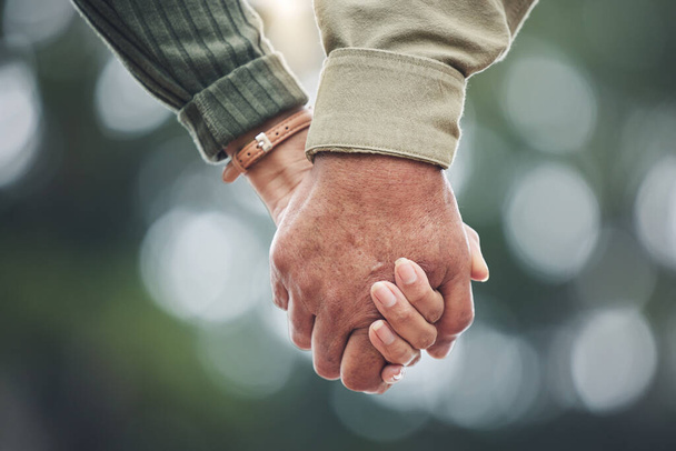 Love, holding hands and couple together in partnership, marriage or people with trust, bonding or moment in nature with bokeh background. Hand, support and unity with a soulmate or romantic partner. - Photo, Image