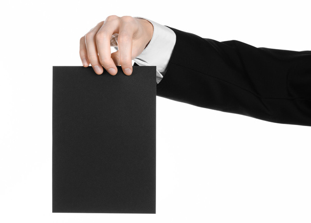 Business and advertising topic: Man in black suit holding a black blank card in hand isolated on white background in studio - Φωτογραφία, εικόνα