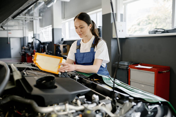 Especialista mecânico fêmea profissional no carro de reparação de serviço de carro envolvido na substituição do filtro de ar do motor - Foto, Imagem