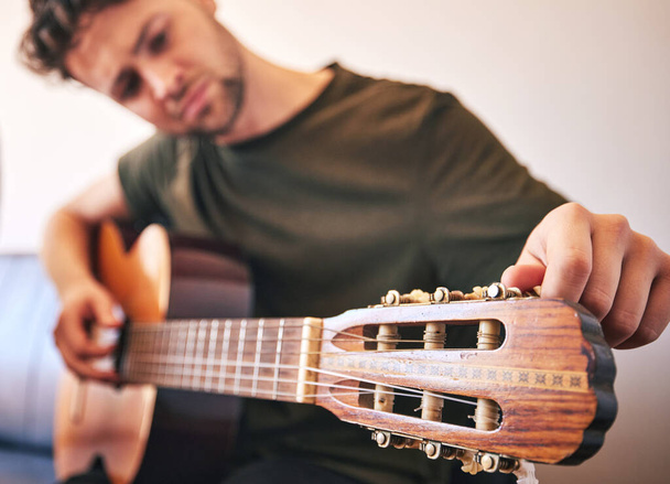 Closeup, man and tuning guitar for music, talent and creative skill of sound production in home studio. Hands, musician and singer check notes of acoustic instrument for audio, performance and artist. - Photo, Image