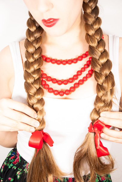 Μια όμορφη κοπέλα με κοτσίδες μακριά ξανθά μαλλιά που φοράει μια πολωνική λαϊκή φορεσιά - Φωτογραφία, εικόνα