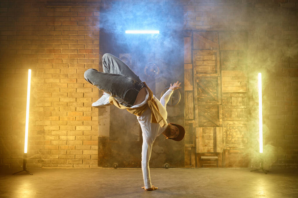 Stüdyoda genç profesyonel dansçı. Yetenekli bir adam hip hop yaparak amuda kalkıyor. Gençlik ve serbest stil performans konsepti - Fotoğraf, Görsel