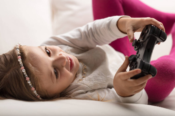 Girl gaming on home sofa, thrilling challenges embraced under parental guidance - 写真・画像