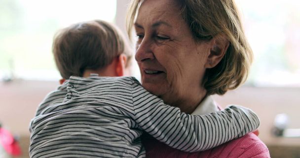 Szczęśliwa babcia trzyma wnuka w ramionach i śmieje się - Zdjęcie, obraz