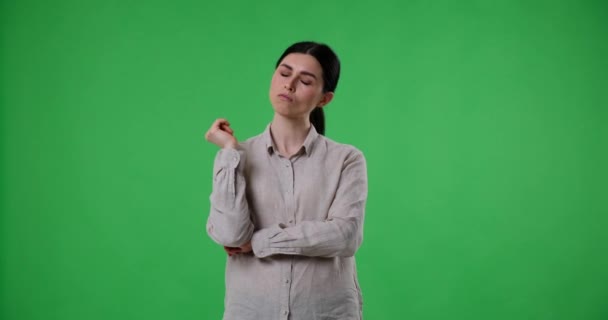 Serieuze blanke vrouw staat tegen een groene achtergrond, diep in gedachten als ze overweegt een keuze of zoekt naar een idee. Ze rust haar hand op haar kin.. - Video