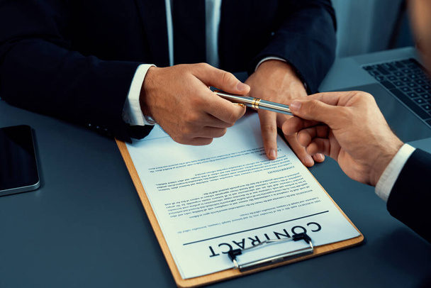 ビジネス取引が行われているとして2人のビジネスマンが机の上に座っています。依頼人またはパートナーが契約書に署名し、契約書を署名で封止するためのペンを与える企業弁護士。フェルベント - 写真・画像