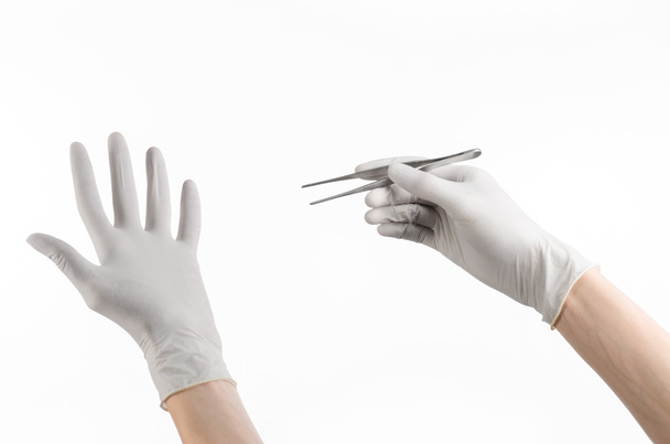 Тема медицини та хірургії: рука лікаря в білій рукавичці, що тримає пінцет ізольовано на білому тлі
 - Фото, зображення