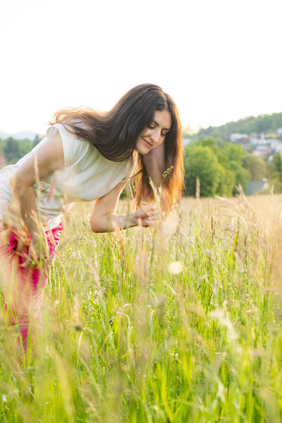 A young woman walks across a field. A walk in nature in the summer - Foto, imagen