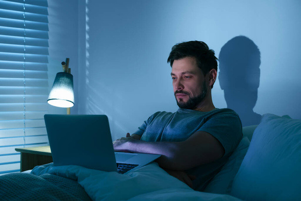 Man using laptop in bed at night. Internet addiction - Zdjęcie, obraz